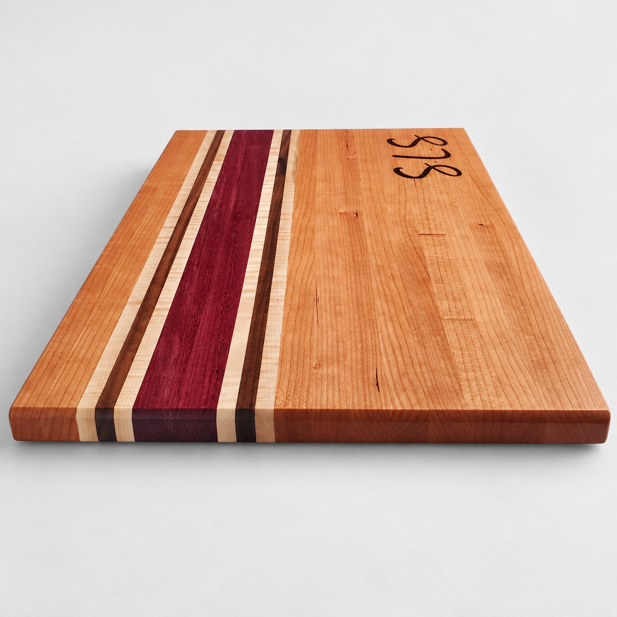 Handcrafted Cherry, Purple Heart, Walnut & Curly Maple Cutting Board, detail view on a light gray background