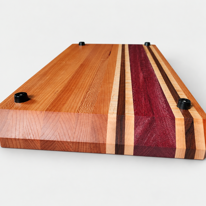 Handcrafted Cherry, Purple Heart, Walnut & Curly Maple Cutting Board, detail view on a light gray background