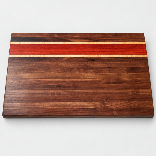 Walnut, padauk and curly maple cutting board on a light gray background